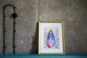 Plakat z Maryją głaszczącą dziecko i modlitwą "Zdrowaś Maryjo". Oprawiony w białe passe-partout i złotą ramę.