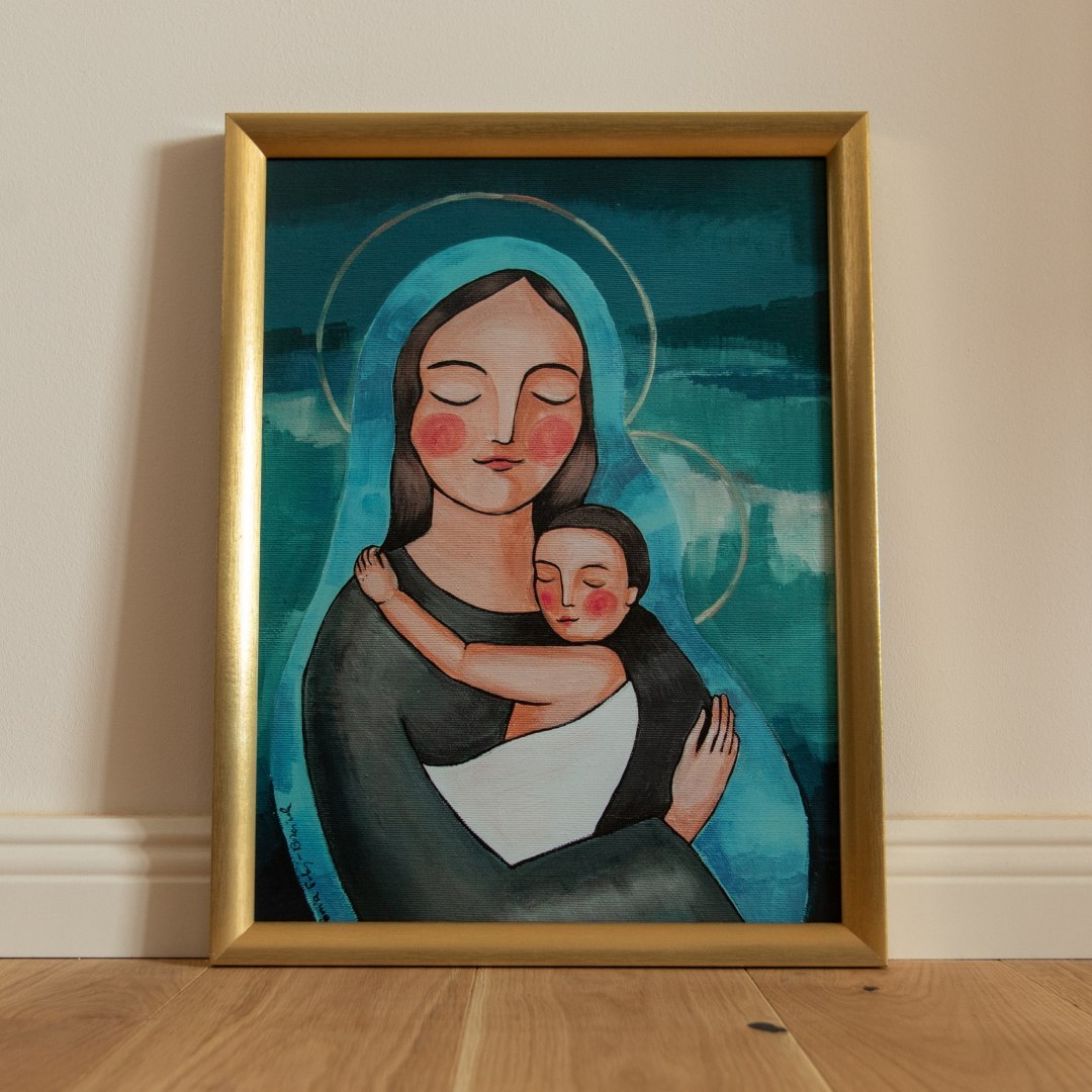 Plakat z Maryją przutulającą małego Jezusa. Oprawiony jest w złotą ramę.