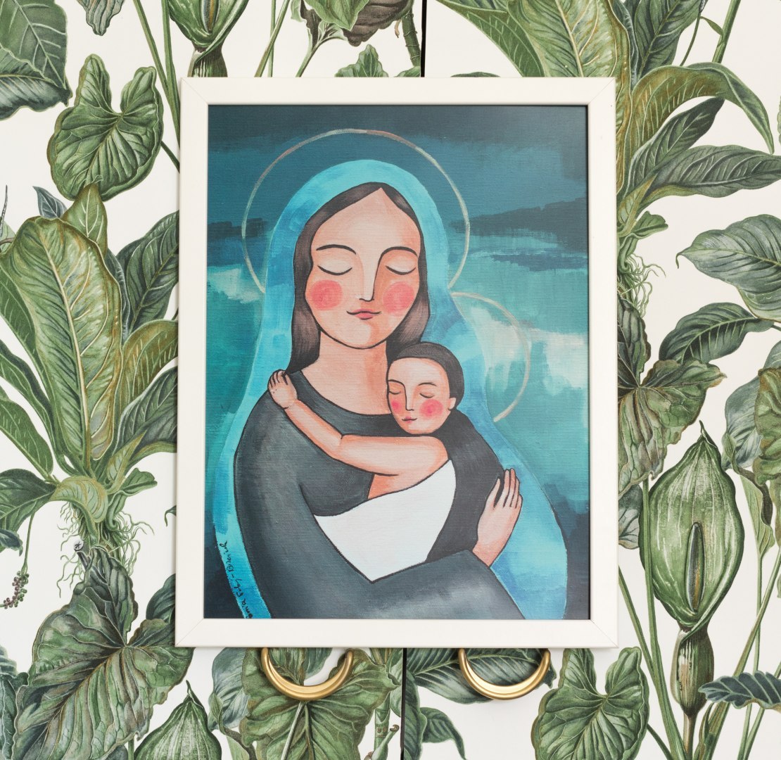 Plakat z Maryją przutulającą małego Jezusa. Oprawiony jest w białą ramę.