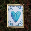 Plakat niebieskim sercem w otoczeniu liściastych gałązek i kwiatów. Oprawiony  w złotą ramę.